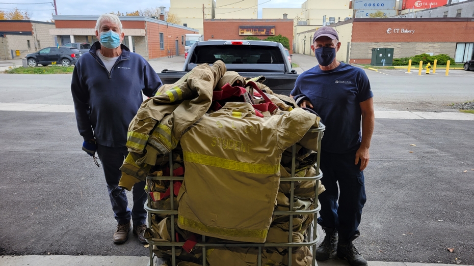 Two retired first responders and GlobalFire volunteers with SLC's donated bunker suits